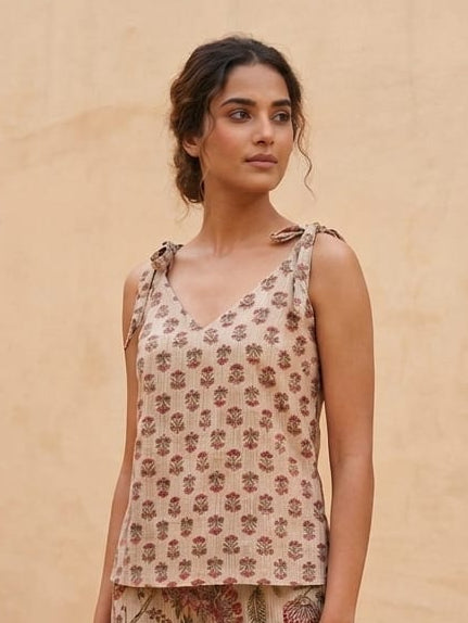 Woman wearing a floral sleeveless top against a beige background